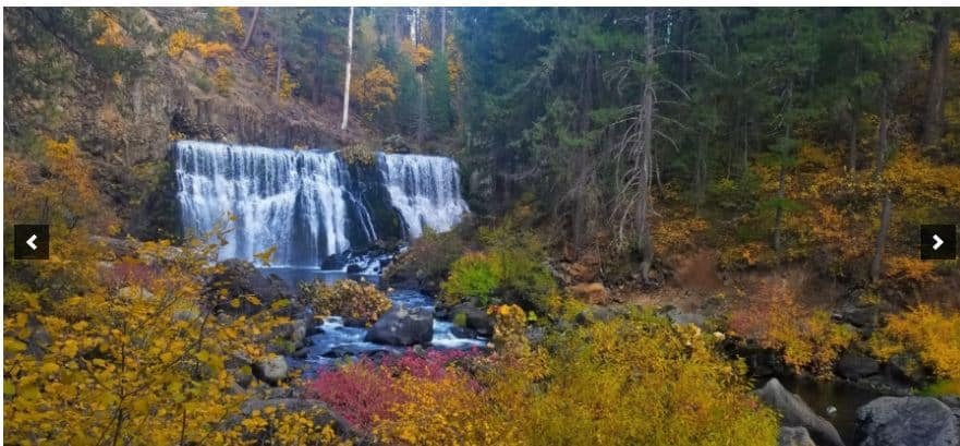 Waterfall surrounded by autumn foliage in a forest scene for outdoor enthusiasts and nature lovers.