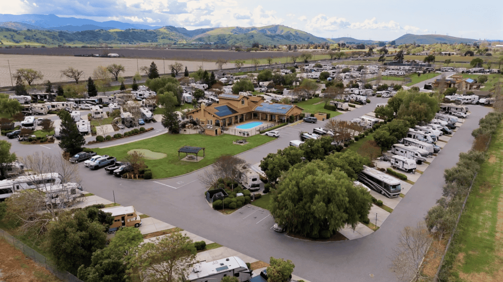 Aerial view of FreeWheelers RV community featuring numerous RVs, well-maintained landscapes, and amenities like a pool and clubhouse in a scenic setting perfect for outdoor enthusiasts and RV travelers.