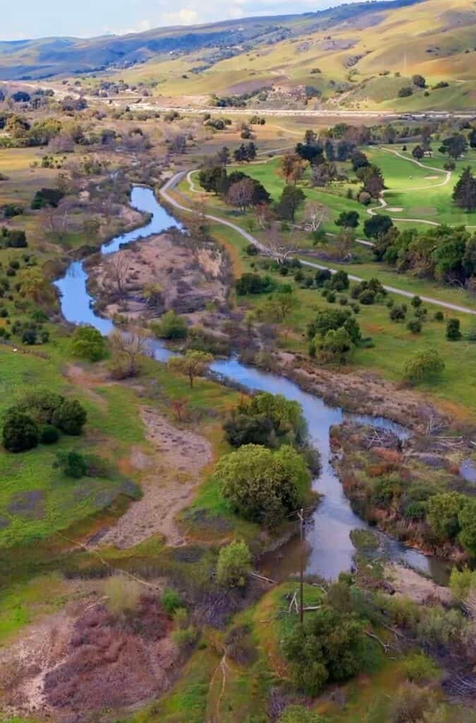 Serene coastal hills with winding river, lush greenery, and scenic bike trails ideal for outdoor recreation and cycling adventures at FreeWheelers.