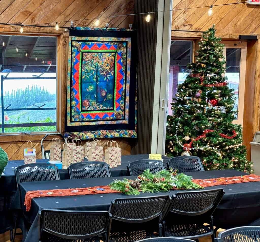 Enjoying RVing, traveling, camping, nature at a festive gathering with a decorated Christmas tree and colorful quilt.